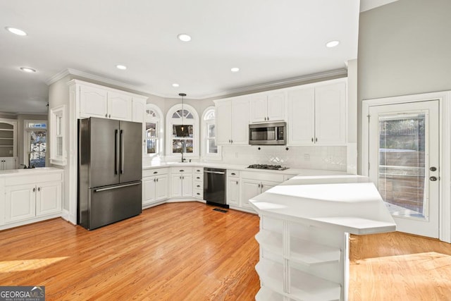 kitchen with tasteful backsplash, kitchen peninsula, white cabinets, and stainless steel appliances