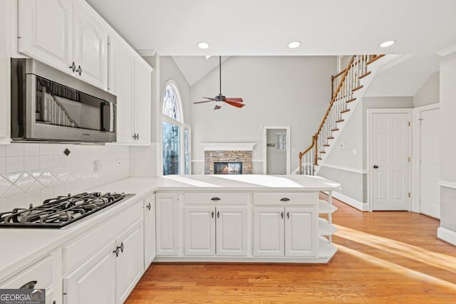 kitchen with white cabinetry, ceiling fan, kitchen peninsula, decorative backsplash, and appliances with stainless steel finishes