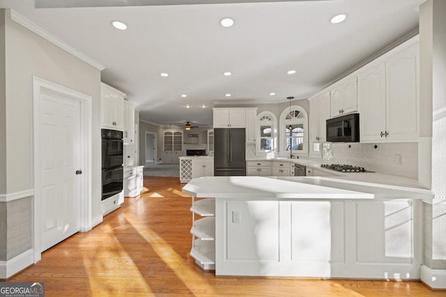 kitchen featuring black appliances, kitchen peninsula, sink, tasteful backsplash, and white cabinetry