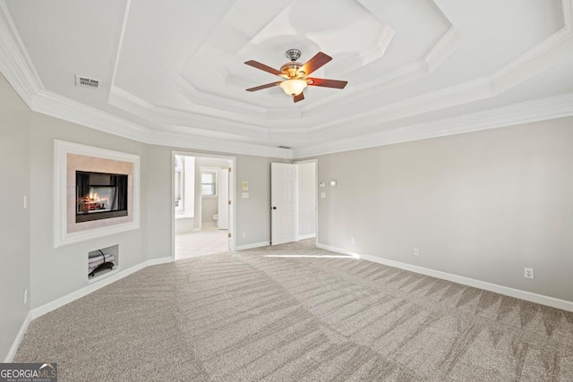 unfurnished living room featuring a tray ceiling, crown molding, ceiling fan, and light carpet