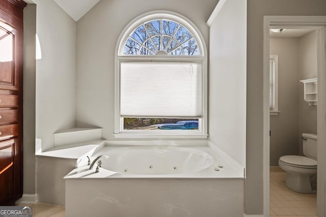 bathroom with tile patterned floors, a tub to relax in, toilet, and lofted ceiling