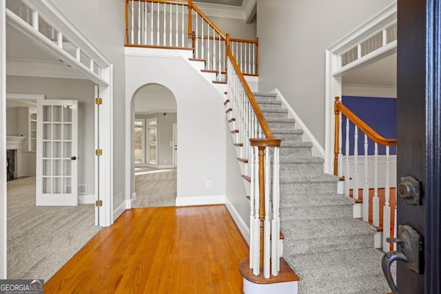 stairs with wood-type flooring and crown molding