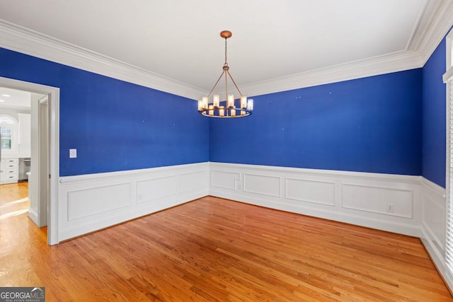 spare room with hardwood / wood-style floors, a notable chandelier, and ornamental molding