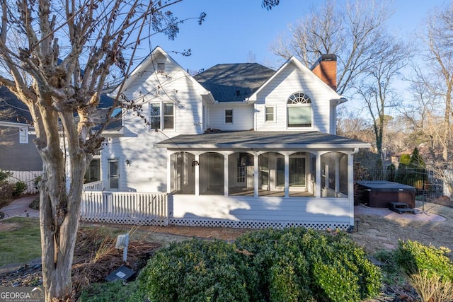 rear view of property with a hot tub