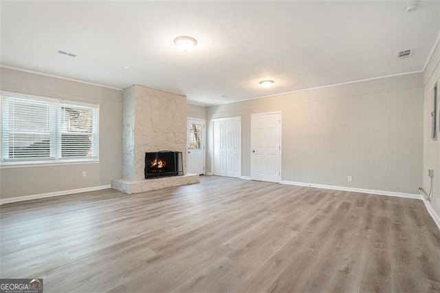 unfurnished living room with light hardwood / wood-style floors, ornamental molding, and a fireplace