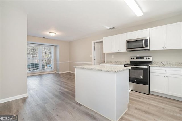 kitchen featuring a center island, white cabinets, light wood-type flooring, light stone counters, and stainless steel appliances