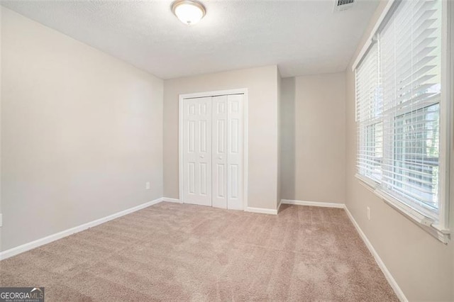 unfurnished bedroom featuring a closet and light colored carpet