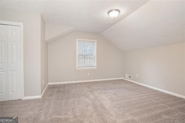 bonus room with light carpet, a textured ceiling, and vaulted ceiling