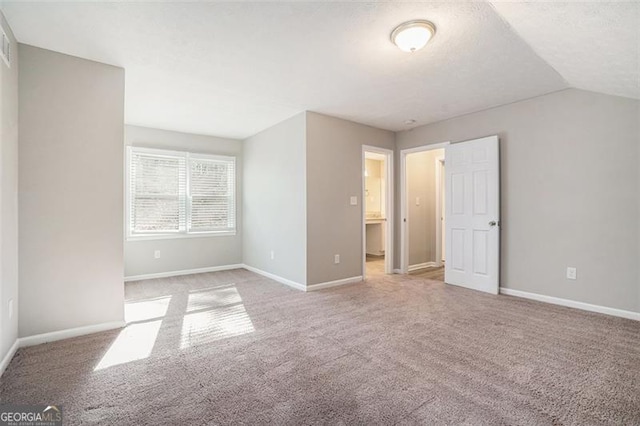 unfurnished bedroom with light colored carpet, a textured ceiling, and vaulted ceiling