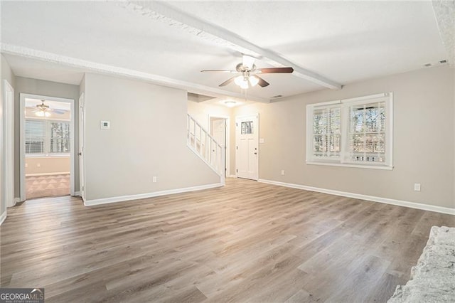 empty room featuring beamed ceiling, hardwood / wood-style floors, and ceiling fan