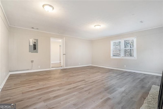 empty room with electric panel and hardwood / wood-style flooring