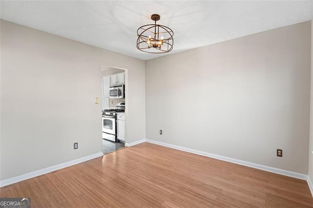 spare room with a chandelier and hardwood / wood-style flooring