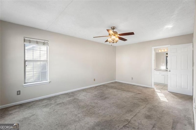 spare room featuring light carpet, ceiling fan, and a textured ceiling