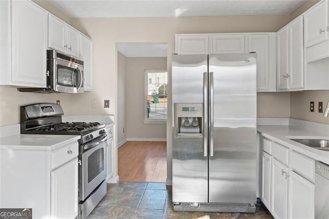 kitchen featuring white cabinetry, sink, stainless steel appliances, and dark tile patterned flooring