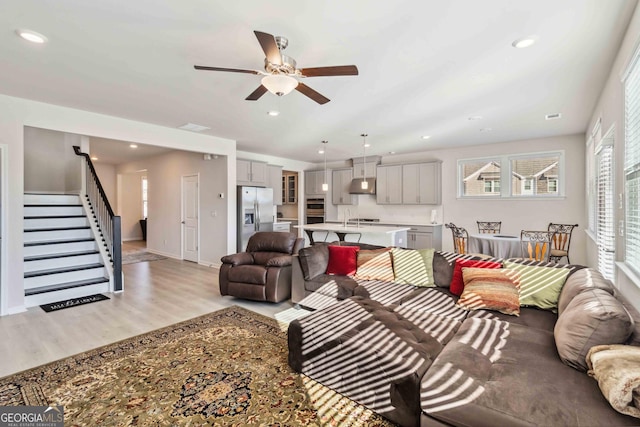 living room with light wood-style floors, a ceiling fan, stairway, recessed lighting, and baseboards