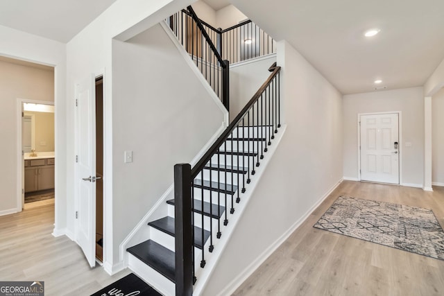 stairs with wood finished floors, baseboards, and recessed lighting