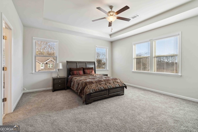 bedroom with a tray ceiling, ceiling fan, and carpet flooring