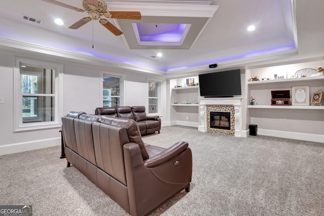 living room with carpet flooring, a raised ceiling, and built in shelves