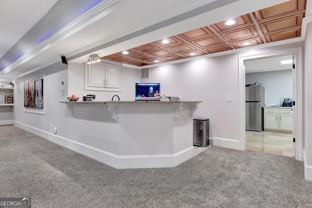 kitchen with light colored carpet, white cabinetry, stainless steel fridge, and kitchen peninsula