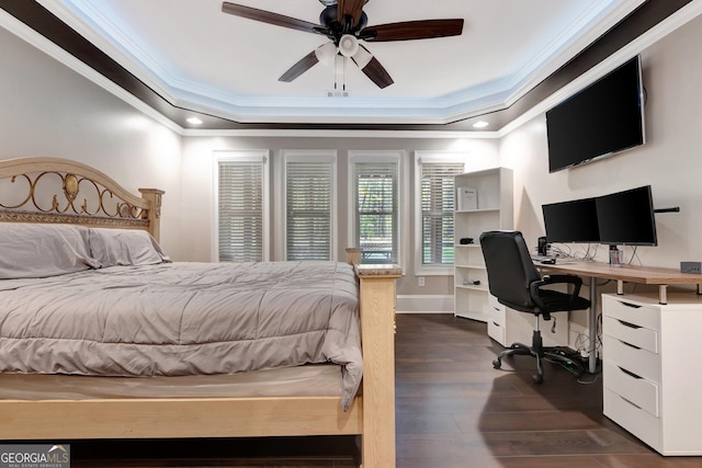 bedroom with dark wood-type flooring, ceiling fan, ornamental molding, and a tray ceiling