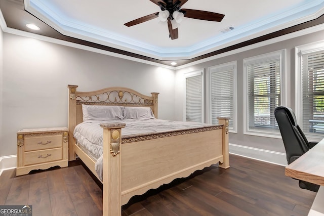 bedroom featuring dark wood-type flooring, ceiling fan, ornamental molding, and a raised ceiling