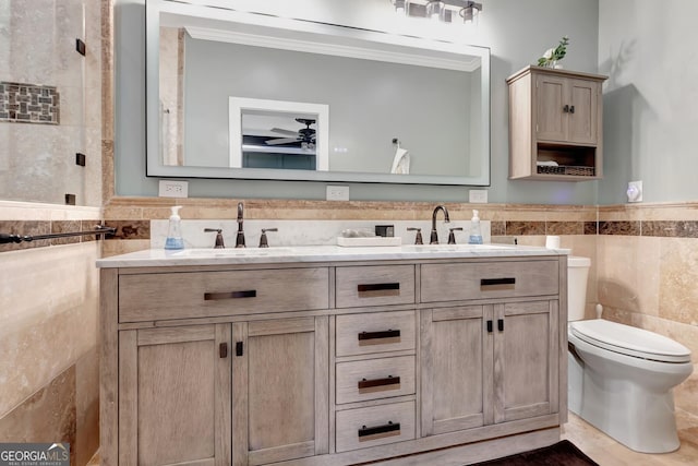 bathroom with toilet, vanity, tile walls, ceiling fan, and ornamental molding