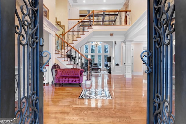 entrance foyer with hardwood / wood-style flooring, a high ceiling, decorative columns, and crown molding