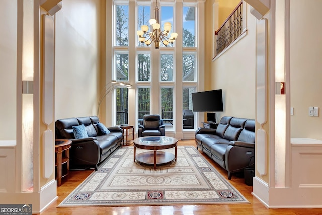 living room with hardwood / wood-style flooring, a chandelier, and a high ceiling