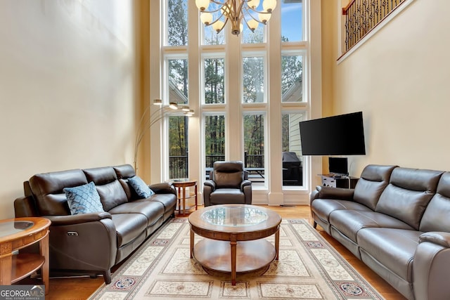 living room with hardwood / wood-style floors, a towering ceiling, and an inviting chandelier