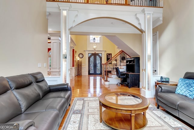 living room with french doors, crown molding, light hardwood / wood-style floors, and ornate columns