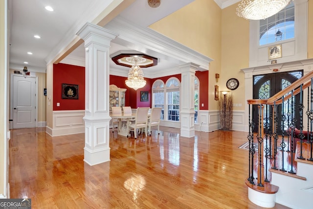 foyer entrance with light wood-type flooring, crown molding, and a chandelier