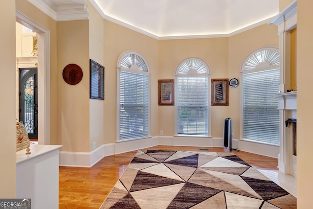 entryway with plenty of natural light, ornamental molding, and light hardwood / wood-style flooring