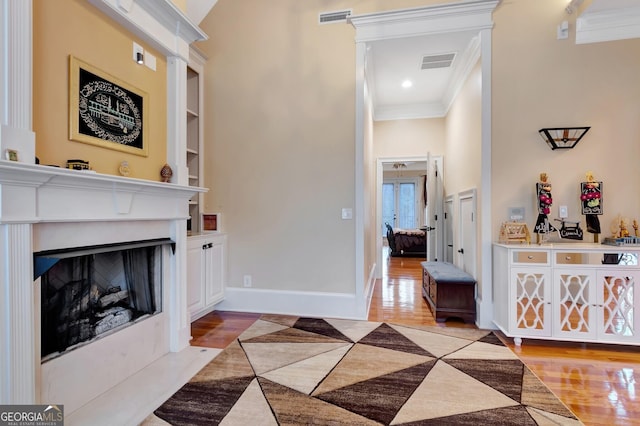 living room with light hardwood / wood-style floors, built in shelves, and ornamental molding