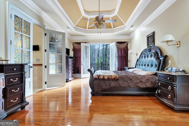 bedroom featuring ornamental molding, access to outside, light wood-type flooring, ceiling fan, and a tray ceiling