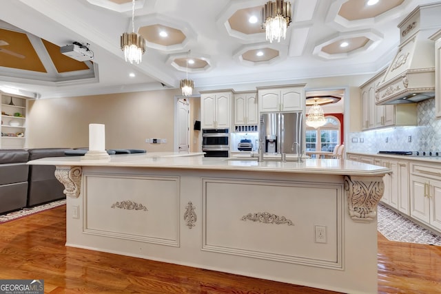 kitchen with hanging light fixtures, stainless steel appliances, and an island with sink