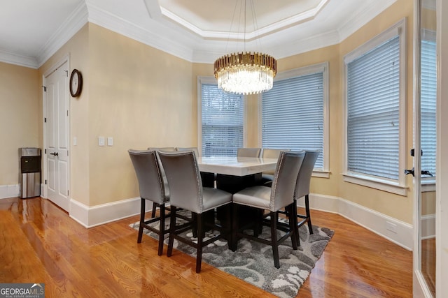 dining room with light hardwood / wood-style floors, a raised ceiling, crown molding, and a chandelier