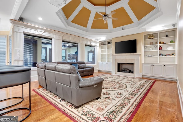 living room with ceiling fan, light hardwood / wood-style floors, coffered ceiling, built in features, and ornamental molding