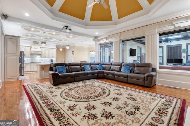 living room with light hardwood / wood-style floors, ornamental molding, and coffered ceiling