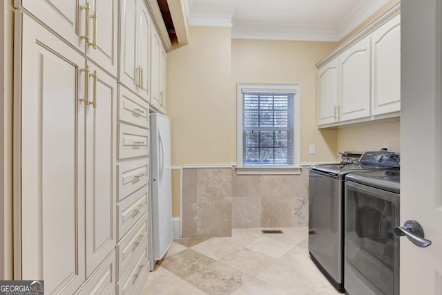 laundry room with tile walls, washing machine and dryer, ornamental molding, light tile patterned floors, and cabinets