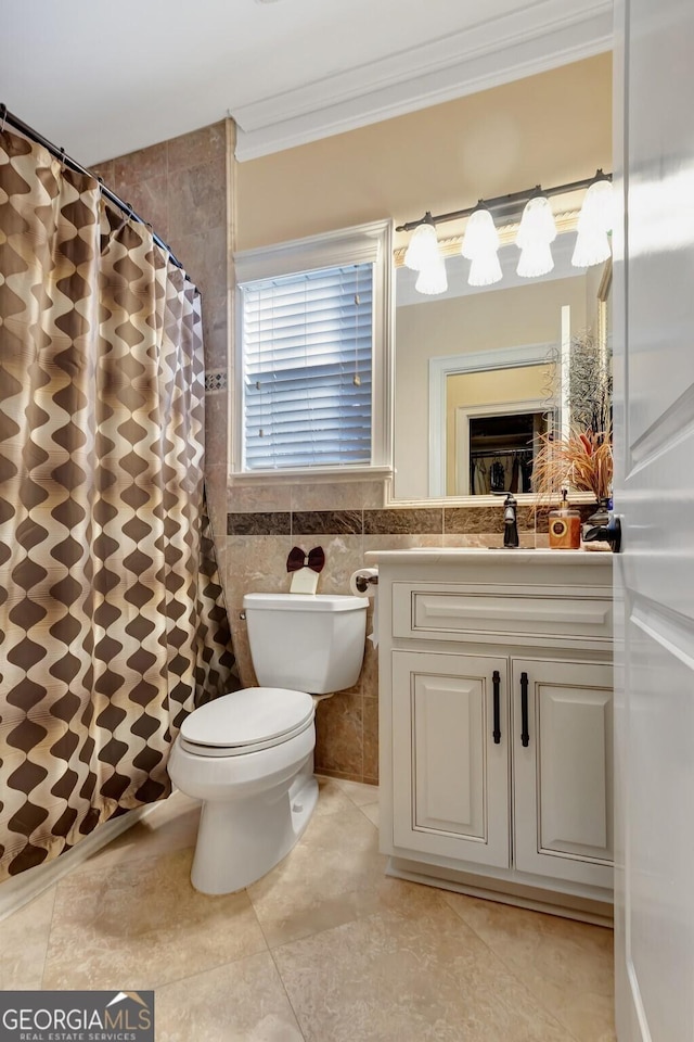 bathroom with walk in shower, vanity, tile walls, tile patterned floors, and ornamental molding