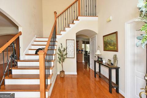 stairway with hardwood / wood-style floors and a towering ceiling