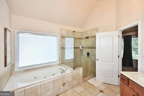 bathroom with tile patterned floors, vanity, lofted ceiling, and plus walk in shower