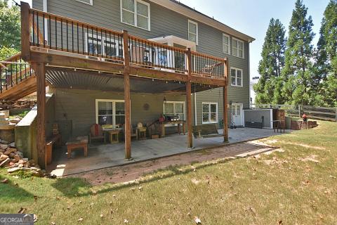 back of property with a wooden deck, a patio area, and a lawn