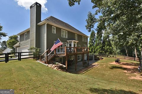 back of property featuring a garage, a lawn, and a wooden deck