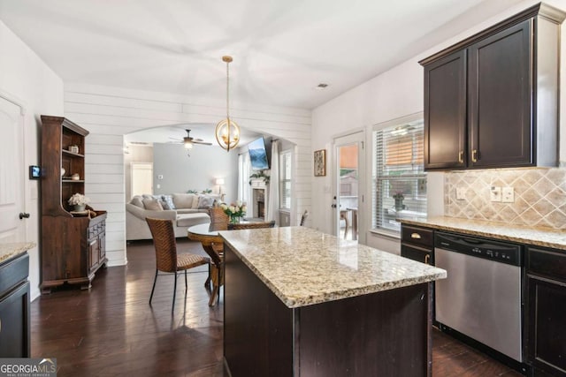 kitchen with dishwasher, hanging light fixtures, ceiling fan, light stone countertops, and a kitchen island