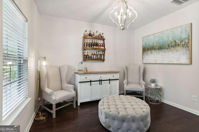 living area with bar area, a chandelier, and dark wood-type flooring