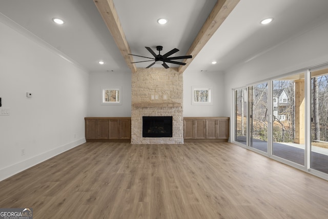 unfurnished living room featuring baseboards, beamed ceiling, wood finished floors, a fireplace, and recessed lighting