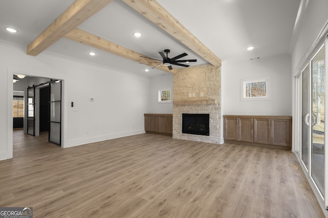 unfurnished living room with a stone fireplace, light wood-style flooring, a ceiling fan, baseboards, and beamed ceiling