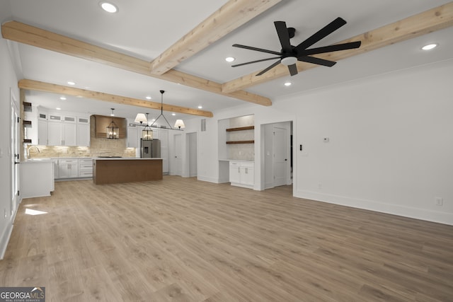 unfurnished living room with beamed ceiling, light wood-style flooring, baseboards, and ceiling fan with notable chandelier