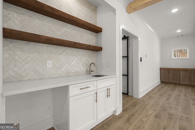 kitchen with beam ceiling, open shelves, light countertops, white cabinets, and a sink